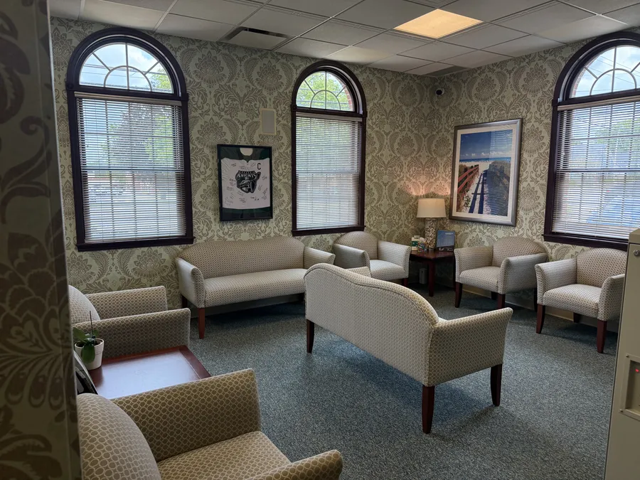 The waiting room, with armchairs, arched windows, and a signed Lake Erie Monsters jersey